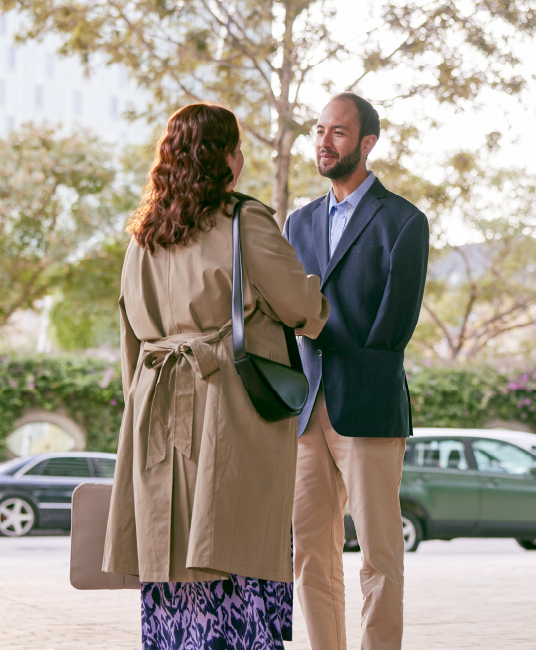 Two people meeting shaking hands outdoors