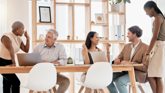 Five coworkers sitting around a desk