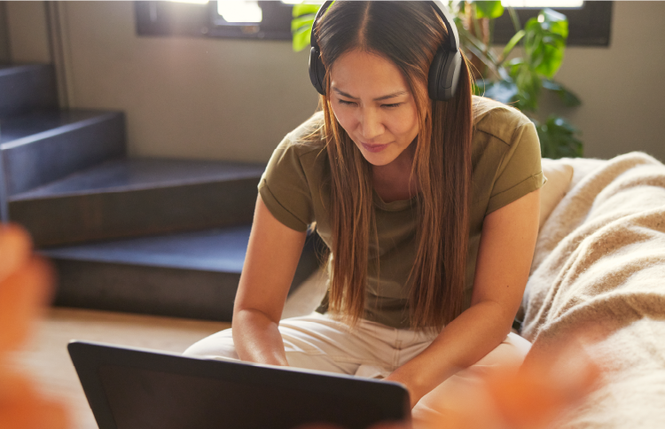 Woman sitting on couch working from home on laptop