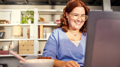 Person sitting at laptop having breakfast while working