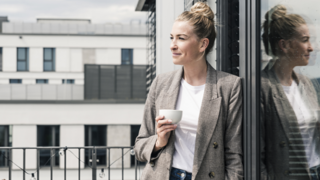 Woman standing and drinking coffee outside near building 