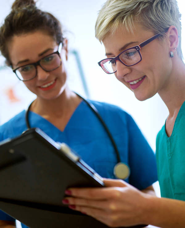 Nurses smiling while looking at handheld tablet 