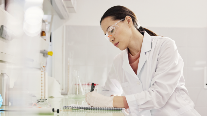 Scientist in lab writing in lab journal 