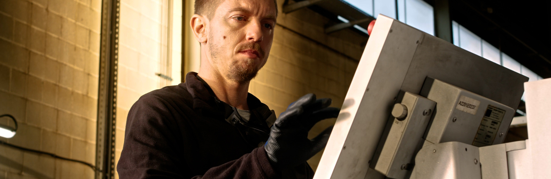 Man standing at a manufacturing machine control panel