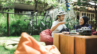 Two individuals enjoying tea outside with Bicycles behind them 