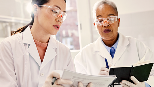 Two people wearing white lab coats reviewing documents