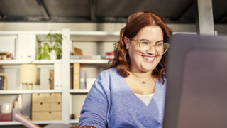 Woman with glassed smiling behind computer