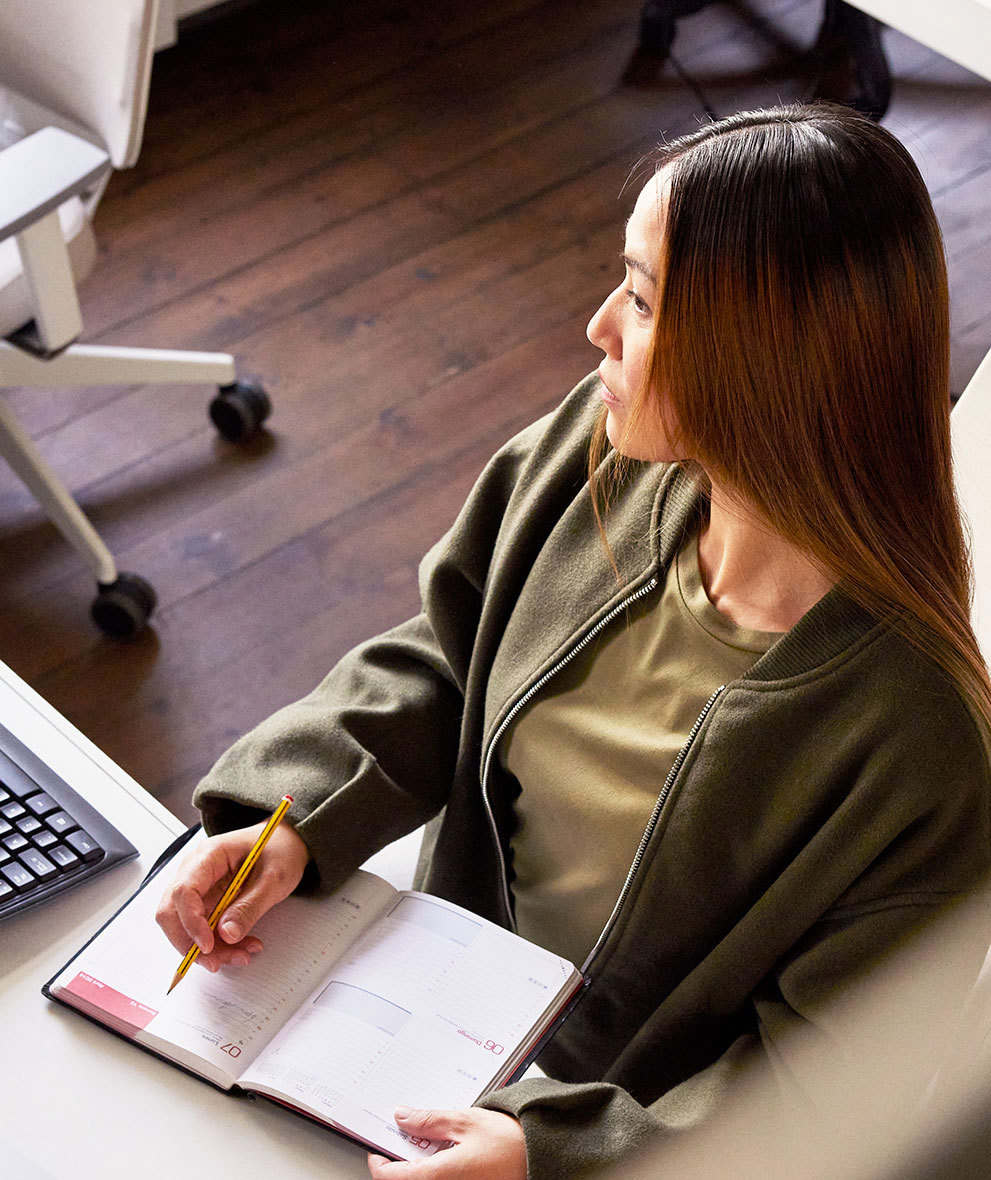 Woman with notebook looking at computer