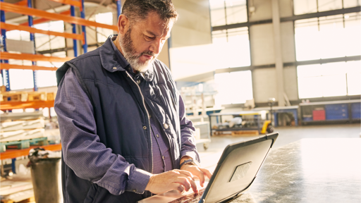 Man standing in a manufacturing building with a laptop