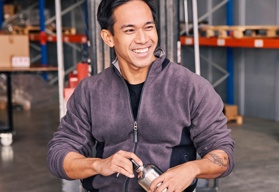 A male worker sitting in a warehouse smiling