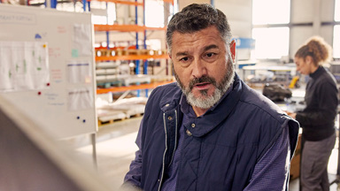 Manufacturing foreperson looking at computer screen with individual in background